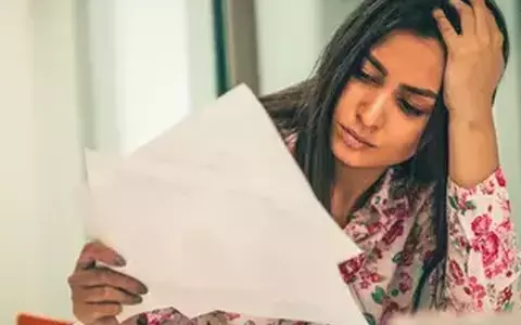 Stressed Person looking at papers with hand on head